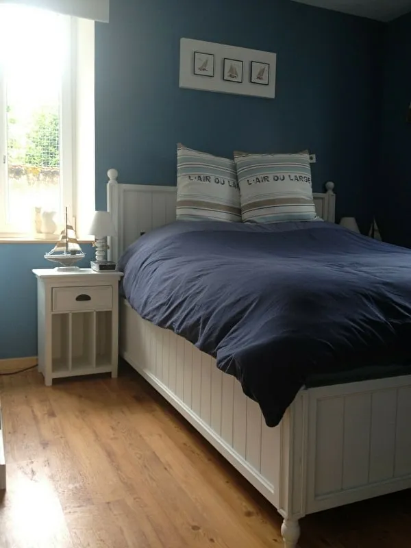 La chambre du Grand Mistral : grand lit blanc, tables de chevet et mur bleu