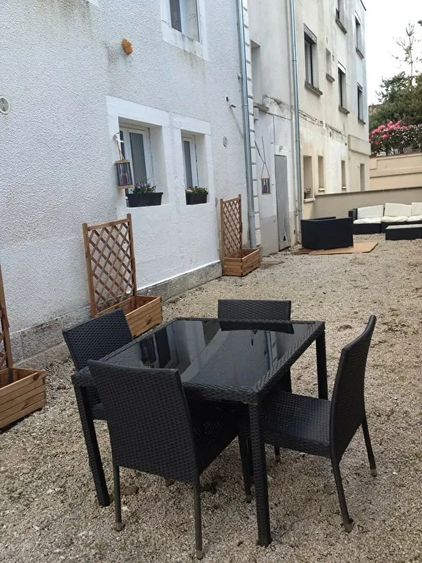 La cour du 6 avenue Jean Moulin : salon de jardin en résine tressée et façade fleurie